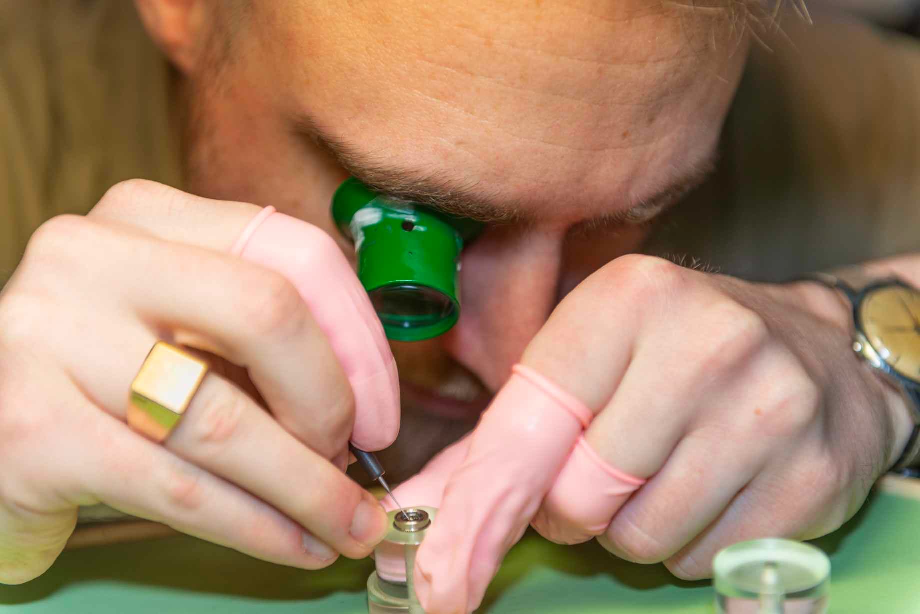 Anders bruger urmagerlup og antistatiske fingerbøle mens han arbejder på et urværk